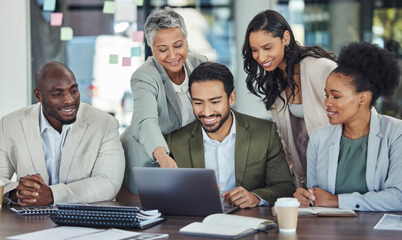 team of coworkers looking at laptop together in a collaborative environment