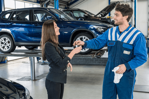 Happy customer receiving car key from technician at service center  