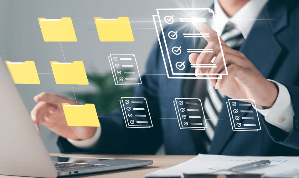 Man using dealer package management system on laptop with folders 